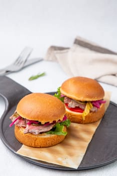 hot burgers with lettuce and vegetables on a wooden board