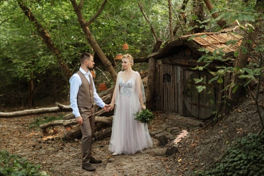 wedding walk of the bride and groom in a coniferous park in summer in elven accessories