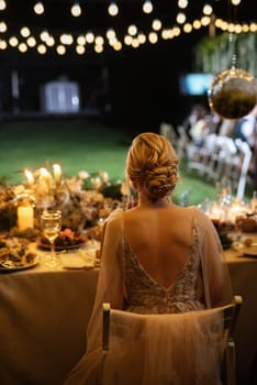 evening wedding family dinner in the forest with light bulbs and candles