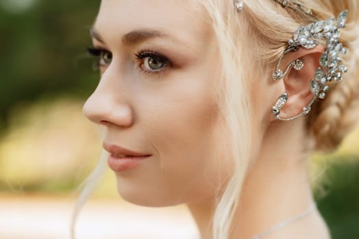 portrait of a happy bride in a light light dress on a green meadow in the park wearing elven accessories