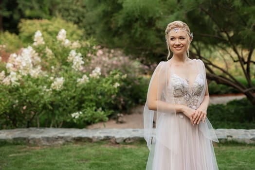 portrait of a happy bride in a light light dress on a green meadow in the park wearing elven accessories