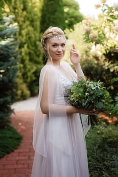 portrait of a happy bride in a light light dress on a green meadow in the park wearing elven accessories