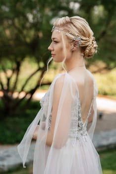 portrait of a happy bride in a light light dress on a green meadow in the park wearing elven accessories