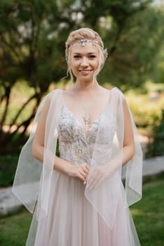 portrait of a happy bride in a light light dress on a green meadow in the park wearing elven accessories