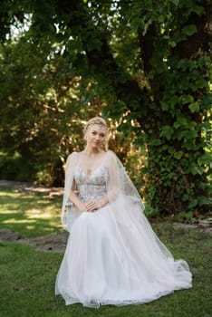 portrait of a happy bride in a light light dress on a green meadow in the park wearing elven accessories