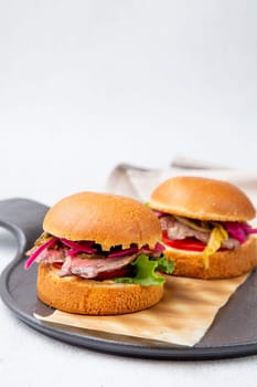 hot burgers with lettuce and vegetables on a wooden board