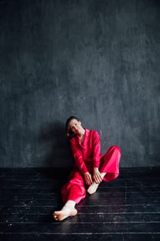Beautiful slender woman in pink pajamas in dark black room