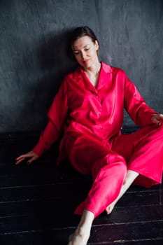 Beautiful slender woman in pink pajamas in dark black room