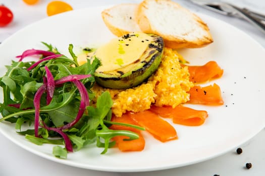 a mix of salmon, arugula salad, white bread and baked avocado with cheese