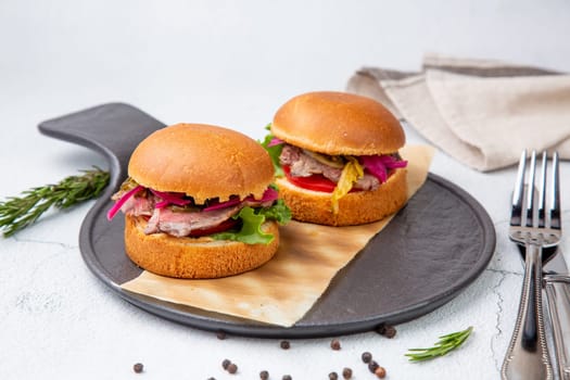 hot burgers with lettuce and vegetables on a wooden board