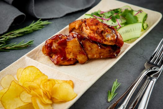 European dish. Chicken in sauce, with fried potatoes and cucumber salad, herbs and onions. dark background