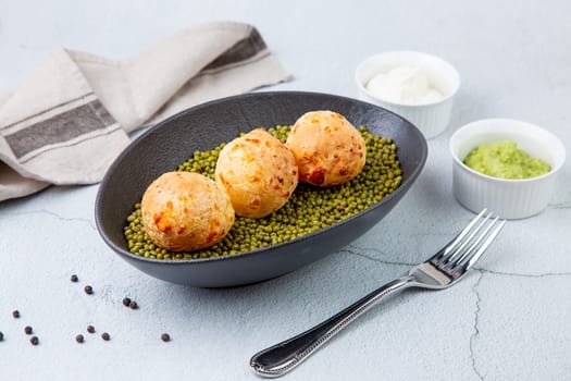 cooked meatballs on peas in an oblong bowl