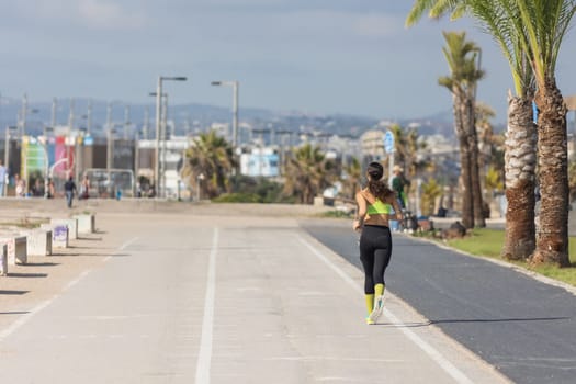 A woman running down a street next to palm trees