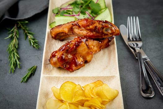 European dish. Chicken in sauce, with fried potatoes and cucumber salad, herbs and onions. dark background