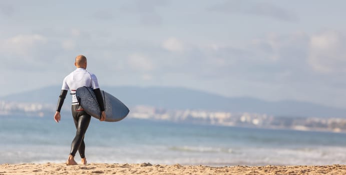 A man carrying a surfboard on top of a sandy beach