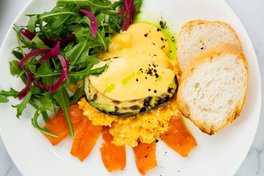 a mix of salmon, arugula salad, white bread and baked avocado with cheese