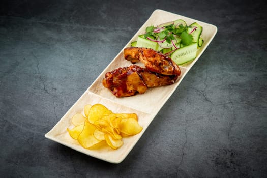 European dish. Chicken in sauce, with fried potatoes and cucumber salad, herbs and onions. dark background