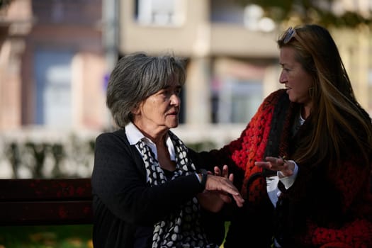 Elderly old cute woman with Alzheimer's very happy and smiling when eldest daughter hugs and takes care of her in park in autumn. Theme aging and parenting, family relationships and social care.