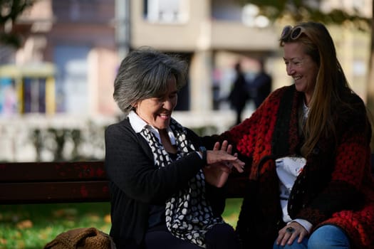 Elderly old cute woman with Alzheimer's very happy and smiling when eldest daughter hugs and takes care of her in park in autumn. Theme aging and parenting, family relationships and social care.