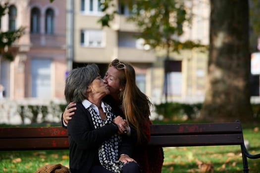 Elderly old cute woman with Alzheimer's very happy and smiling when eldest daughter hugs and takes care of her in park in autumn. Theme aging and parenting, family relationships and social care.