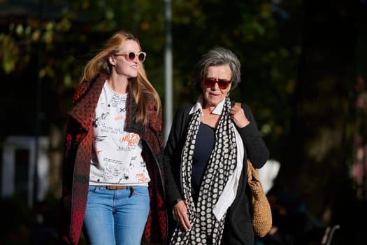 Elderly old cute woman with Alzheimer's very happy and smiling when eldest daughter hugs and takes care of her in park in autumn. Theme aging and parenting, family relationships and social care.