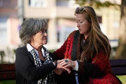 Elderly old cute woman with Alzheimer's very happy and smiling when eldest daughter hugs and takes care of her in park in autumn. Theme aging and parenting, family relationships and social care.