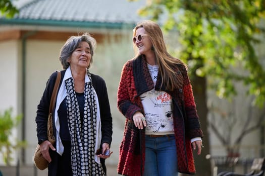 Elderly old cute woman with Alzheimer's very happy and smiling when eldest daughter hugs and takes care of her in park in autumn. Theme aging and parenting, family relationships and social care.