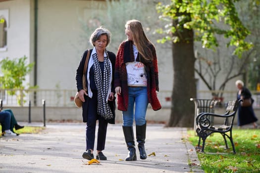 Elderly old cute woman with Alzheimer's very happy and smiling when eldest daughter hugs and takes care of her in park in autumn. Theme aging and parenting, family relationships and social care.