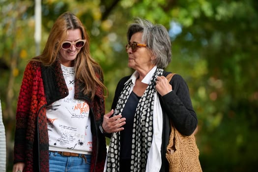 Elderly old cute woman with Alzheimer's very happy and smiling when eldest daughter hugs and takes care of her in park in autumn. Theme aging and parenting, family relationships and social care.