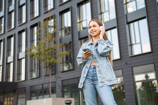 Young fair haired woman in headphones selects music on smart phone.