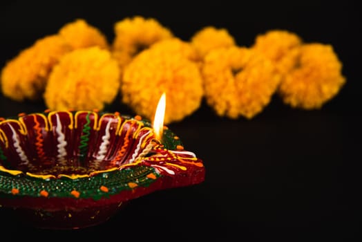 Diwali's beauty revealed, A beautifully adorned Diwali lamp and ornate flower rangoli on a dramatic black backdrop. Ideal for festive invitations, ceremonies, and celebrations.