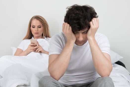 Family conflict concept, addicted to cellphone woman and upset man on bed