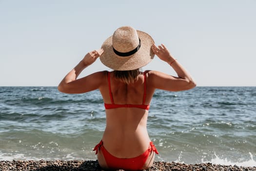 Woman travel sea. Young Happy woman in a long red dress posing on a beach near the sea on background of volcanic rocks, like in Iceland, sharing travel adventure journey