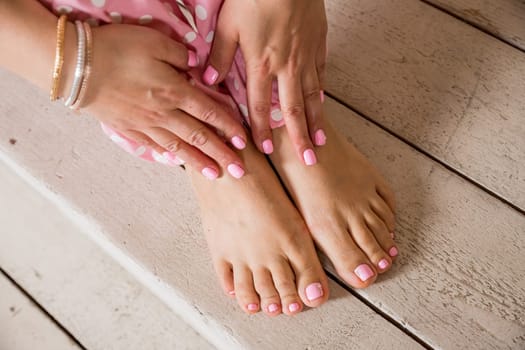 Nail spa procedure. Manicure and pedicure. Female hands and feet on pink background top view.