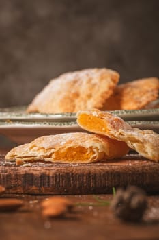 A crescent-shaped pastry whose filling is made of eggs and almonds wrapped in crispy dough, cut in an artisanal way and sprinkled with sugar.