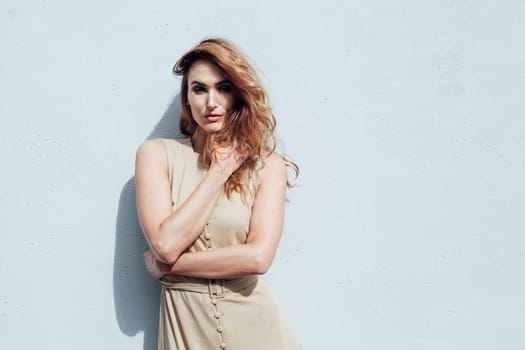 Portrait of a beautiful fashionable woman in a beige dress against a grey background