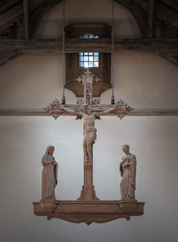 Liverpool, UK - Oct 07, 2023 - The Rood, hanging above the altar. Jesus hanging on the cross and The Virgin Mary and St.John (The evangelist) statues at Our Lady and St Nicholas Church, The figure of Jesus Christ, Space for text, Selective focus.