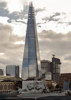 London, UK - Nov 07, 2023 - View of The Shard skyscraper, The tallest building with HMS Belfast warship museum on River Thames in front of it. Space for text, Selective focus.