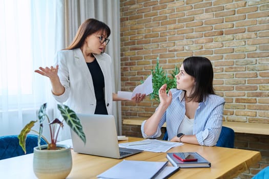 Two serious surprised business women colleagues sitting at large table in office with business papers contracts. Business ceo work law finance mentoring consulting teamwork people job concept