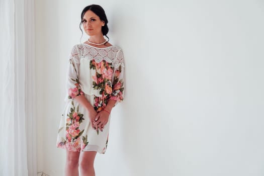 Portrait of a woman in a dress with flowers in a white room