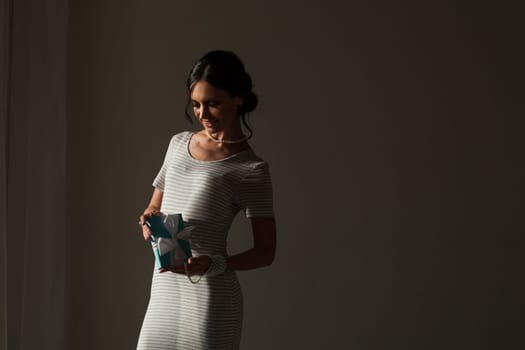 portrait of a woman with a gift in a striped gray white dress