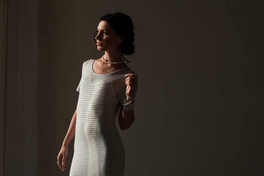 brunette woman in a striped gray white dress