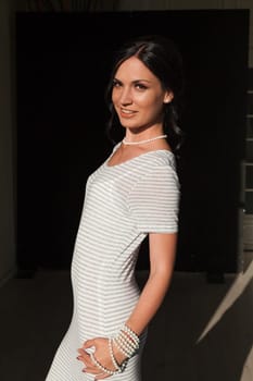 brunette woman in a striped gray white dress