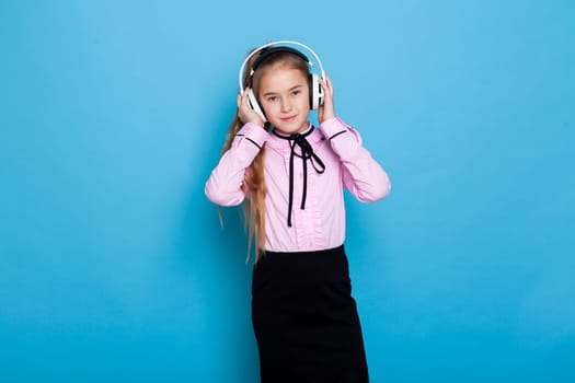 Schoolgirl girl listens to music in headphones