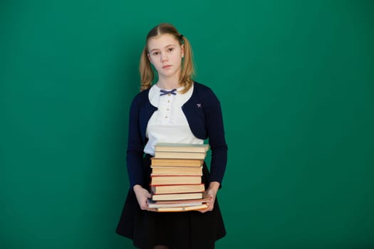 Schoolgirl girl stands off the internet with lots of books off the classroom
