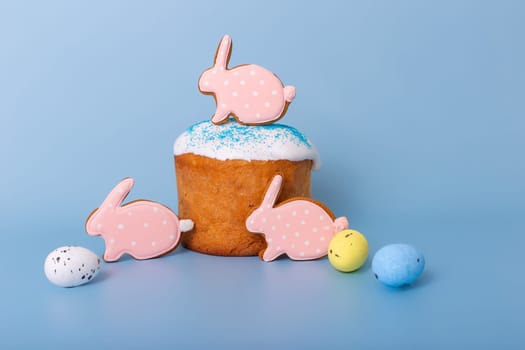 Three cute pink gingerbreads in the form of a rabbit on Easter cake stand on a blue background.