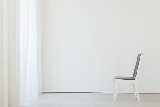 one gray chair in an empty white interior room
