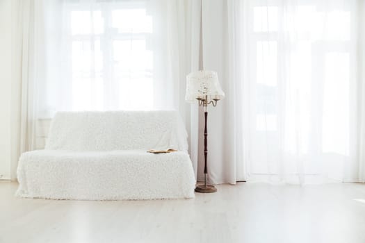 white sofa with a book in the interior of a room with windows