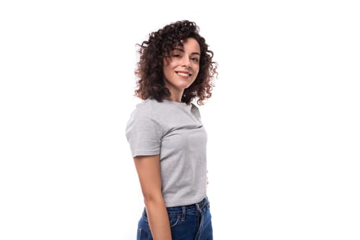 pretty confident authentic young curly brunette woman in gray t-shirt on white background with copy space.