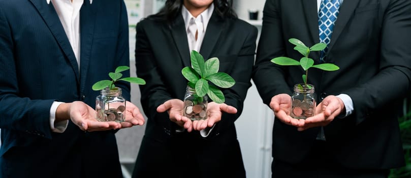 Business people holding money savings jar filled with coins and growing plant for sustainable financial planning for retirement or eco subsidy investment for environment protection. Quaint